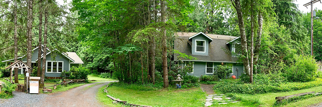 Mountain Meadows Inn’s gray exterior and wooded grounds in Ashford